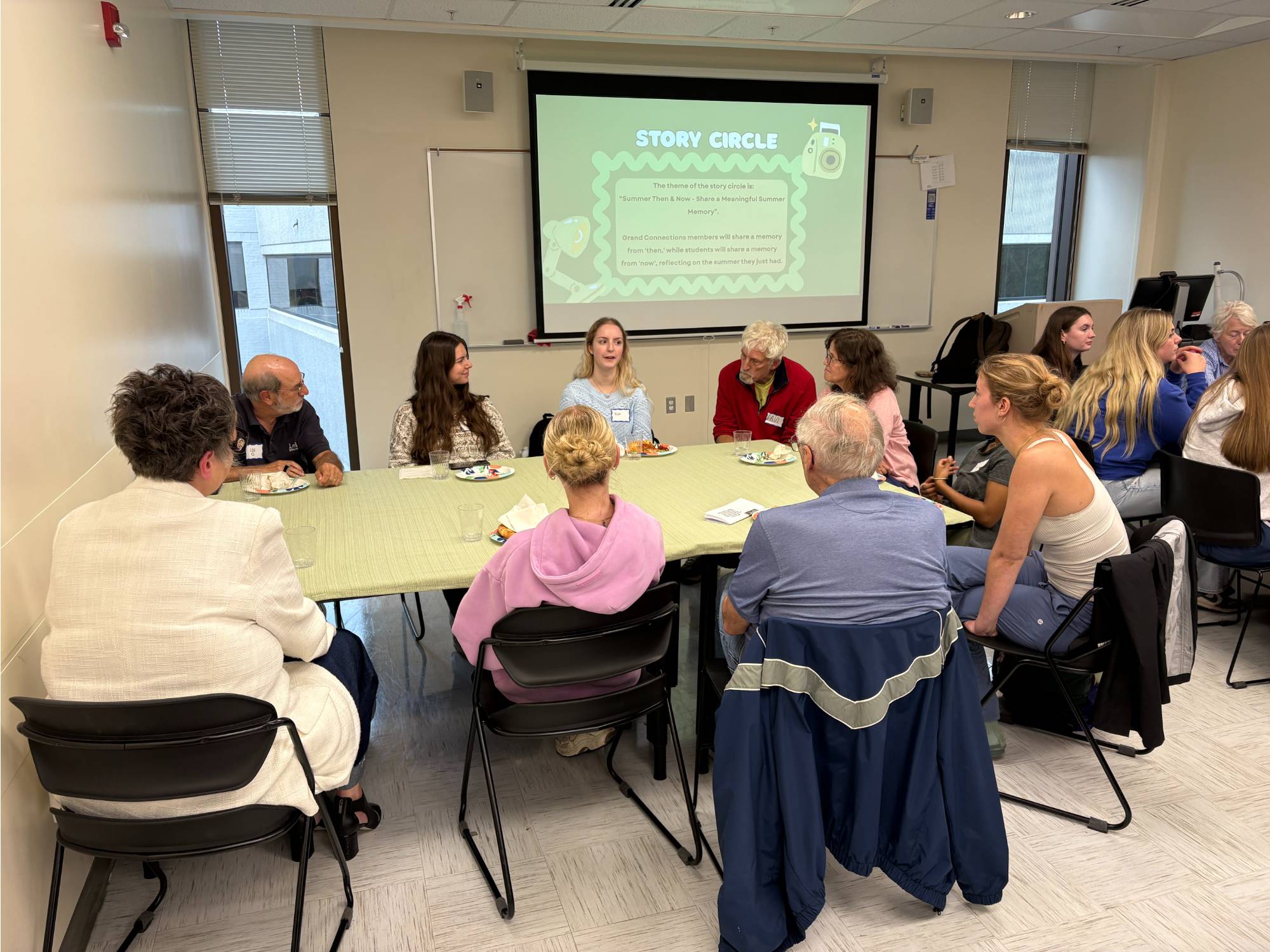 SAGE and Grand Connection members having a conversation at a table while eating pizza
